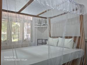 a bedroom with a canopy bed with white pillows at Koala Homestay in Weligama