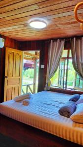 Cette chambre comprend un grand lit et un plafond en bois. dans l'établissement ปารมีฟาร์มสเตย์, à Ban Chao Nam