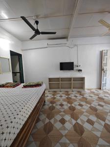 a white room with a bed and a flat screen tv at Kulswami Cottage Alibaug in Alibaug