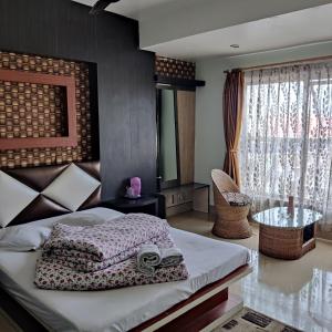 a bedroom with a bed and a table and a window at Hotel Mountain View in Kalimpong