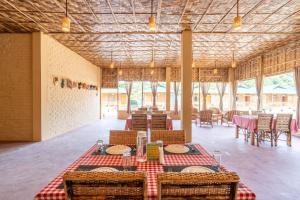 une salle à manger avec des tables et des chaises dans un bâtiment dans l'établissement HABITAS RHINO BY NATURE HUNT, à Kāziranga