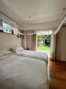 a bedroom with two beds and a large window at Forest Hideaway ~ Rustic in Coromandel Town