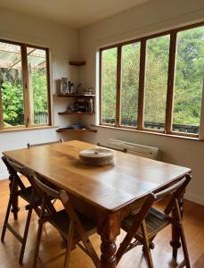 a large wooden table in a room with windows at Forest Hideaway ~ Rustic in Coromandel Town