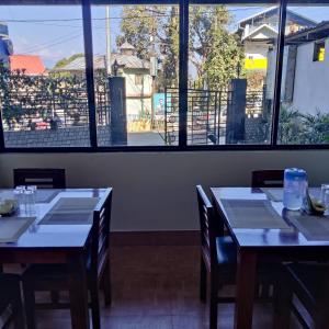 two tables in a restaurant with a large window at Hotel Mountain View in Kalimpong