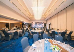 un salón de banquetes con mesas, sillas y una pantalla en Astara Hotel Balikpapan, en Balikpapan