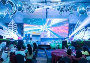 a group of people sitting at tables in front of a stage at Astara Hotel Balikpapan in Balikpapan