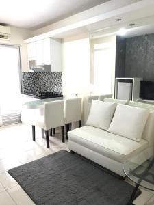a living room with a white couch and a kitchen at Apartemen Kalibata City By Diamond Property in Jakarta