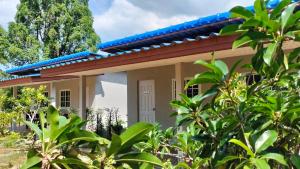 uma casa com um telhado azul e algumas árvores em ปารมีฟาร์มสเตย์ em Ban Chao Nam