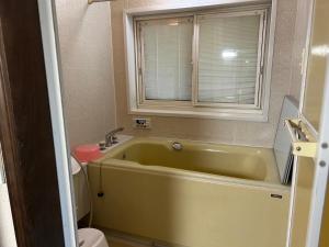 ein Bad mit einer grünen Badewanne und einem Fenster in der Unterkunft 晋～SHIN～各務原 in Kakamigahara