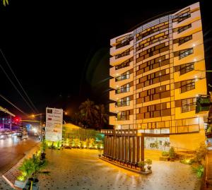 a tall yellow building at night next to a street at Hotel Parami in Yangon