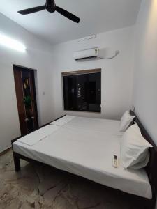 uma cama branca num quarto com uma ventoinha de tecto em Alam Home Stay em Cochin