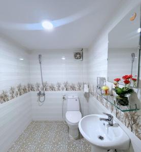 a white bathroom with a toilet and a sink at Amy 2 Hostel Hue in Hue