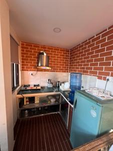 a small kitchen with a brick wall at Avocado Cottages in Khadkagaon