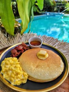 een bord ontbijtproducten met roerei en pannenkoeken bij 11th Earth Farm and Resort in Nabua
