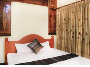 a bedroom with a bed with a wooden headboard and curtains at Keanthay Guest House in Battambang