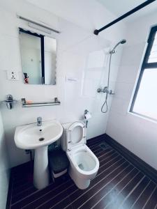 a white bathroom with a sink and a toilet at Avocado Cottages in Khadkagaon