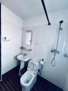 a white bathroom with a toilet and a sink at Avocado Cottages in Khadkagaon
