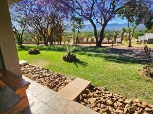 a garden with rocks and trees in a yard at Berlouri Guest House in Hekpoort