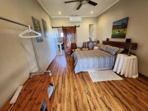 a bedroom with a bed and a wooden floor at Berlouri Guest House in Hekpoort