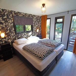 Schlafzimmer mit einem Bett mit gemusterter Wand in der Unterkunft Boschalet Noord Veluwe in Doornspijk