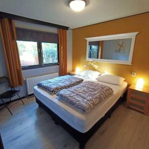 ein Schlafzimmer mit einem großen Bett und zwei Fenstern in der Unterkunft Boschalet Noord Veluwe in Doornspijk