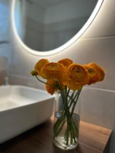 un vaso pieno di fiori d'arancio seduto su un tavolo di Rhospitality - B&B Villa Milano a Cornaredo