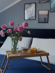 un jarrón de flores rosas sobre una mesa con dos tazas en Rhospitality - B&B Villa Milano, en Cornaredo