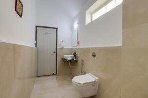 a bathroom with a white toilet and a window at StayVista's Bhils Kabeela - Kanha - Outdoor Pool, Games Room & Kids Zone in Kānha +11 photos