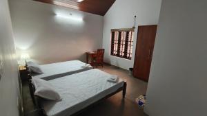 a small room with two beds and a window at SARAS HOME ALAPPUZHA BEACH in Alleppey