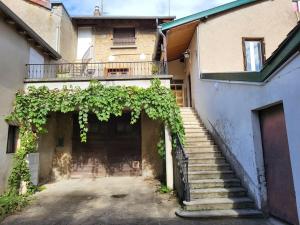 ein Gebäude mit einer Treppe und einem Balkon mit Weinreben in der Unterkunft Gite la ferme des maraîchers in Albigny-sur-Saone