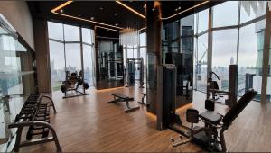 a gym with cardio equipment in a building with windows at Asok - Din Daeng Apartment in Bangkok