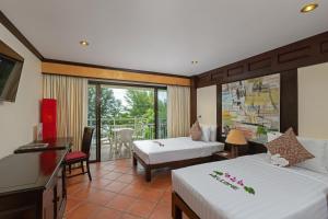 a hotel room with two beds and a balcony at The Front Village - SHA Plus in Karon Beach