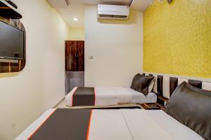 a small room with two beds and a tv at Golden Tulipz Boutique in Mumbai