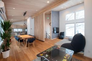 a living room with a table and a kitchen at Moraine Onsen Chalet in Niseko