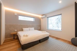 a bedroom with a large bed with a window at Moraine Onsen Chalet in Niseko
