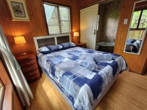 a bedroom with a bed with a blue comforter at Blyde River Cabins in Hoedspruit