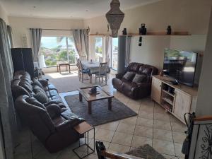 een woonkamer met leren banken en een televisie bij Captains View in Jeffreys Bay