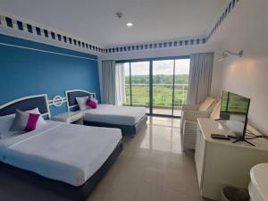 een hotelkamer met 2 bedden en een televisie bij Rua Rasada Express in Trang