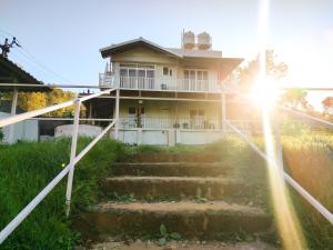 a house with stairs in front of the sun at Cloud & Mist Inn, Kotagiri in Kotagiri