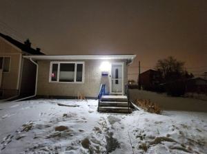 a house with a light on the door in the snow at Like Home in Regina