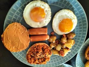 a blue plate with eggs and sausage and other food at Taakradan Valley Resort ท่ากระดานวัลเล่ย์ รีสอร์ท in Si Sawat