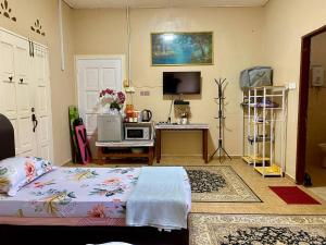 a bedroom with a bed and a desk with a tv at COZY GL Roomstay ARAU in Kangar
