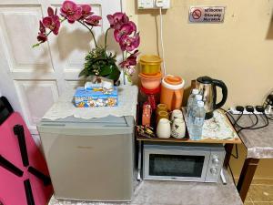 einen Tisch mit einer Mikrowelle und einem Tisch mit Blumen in der Unterkunft COZY GL Roomstay ARAU in Kangar