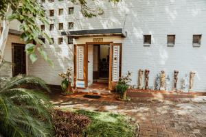 um edifício branco com uma porta com plantas na frente em Ons Dorpshuis Guesthouse em Rustenburg