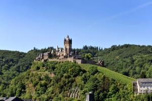 a castle on top of a hill with houses at Hotel Zehnthof in Cochem