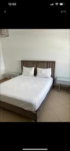 a bed with white sheets and pillows and a table at Duplex corniche lac 2 in Tunis