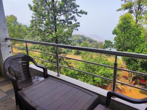 a bench sitting on a balcony with a view at Hotel Oneness Palace in Mahabaleshwar