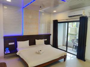 a bedroom with a large bed with a large window at Hotel Oneness Palace in Mahabaleshwar
