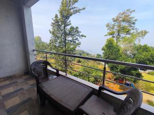 een bank op een balkon met uitzicht op de bomen bij Hotel Oneness Palace in Mahabaleshwar