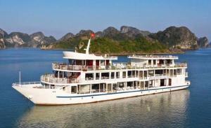 un crucero en el agua con montañas al fondo en Halong Sapphire Cruises, en Ha Long